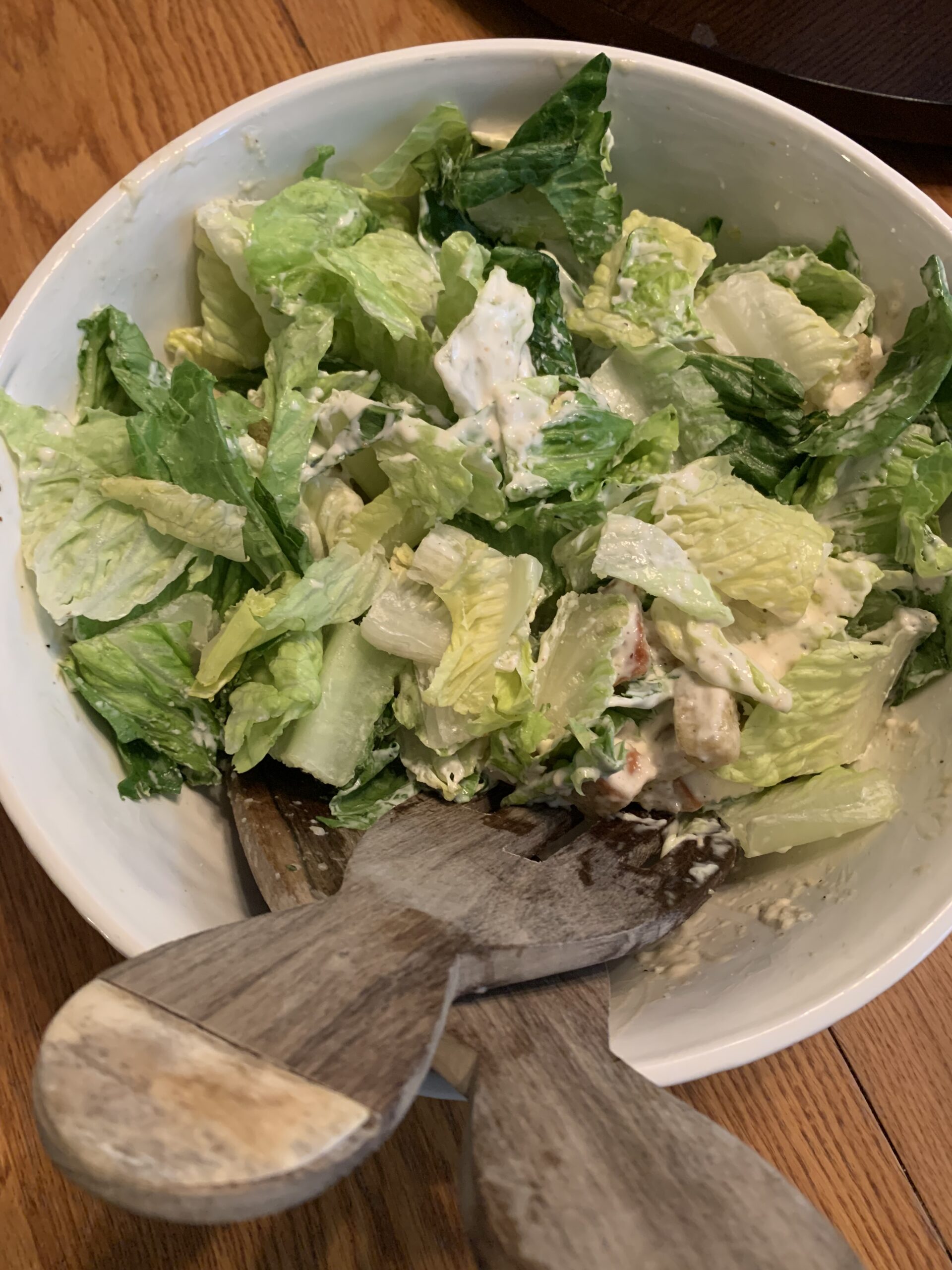 Caesar Salad in a bowl with tongs.