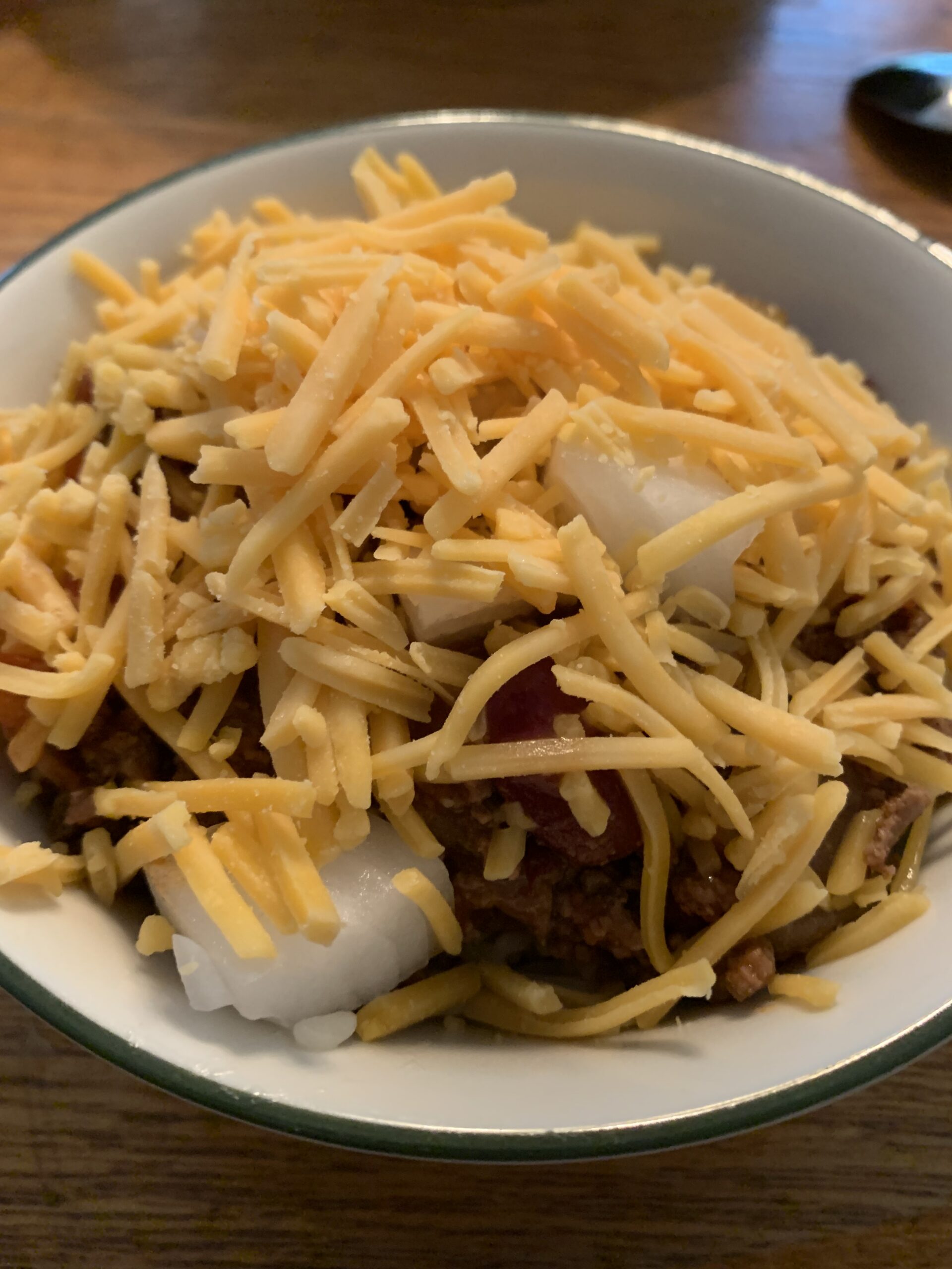 Bowl of chili with cheese and onions